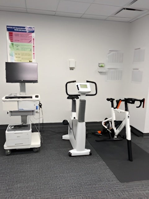 COSMED metabolic cart positioned beside a COSMED modular ergometer bike and a stationary bike in the lab