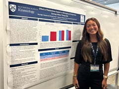 Student researcher smiling next to a research poster presentation during an academic showcase