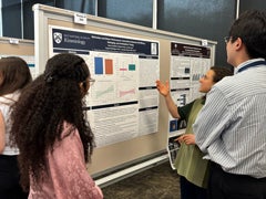 Students discussing academic research findings in front of a poster presentation