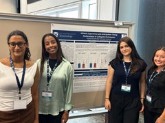 Group of student researchers posing together in front of their department research poster