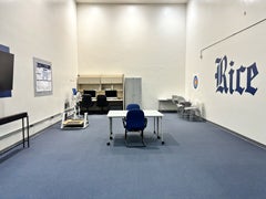 Wide interior view of the Movement Behavior Lab showing computer workstations, testing tables, and a Rice logo on the wall