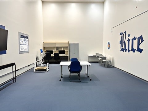Wide interior view of the Movement Behavior Lab showing computer workstations, testing tables, and a Rice logo on the wall