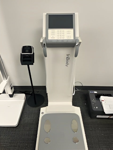 InBody 770 body composition analyzer standing against a white wall with integrated hand electrodes