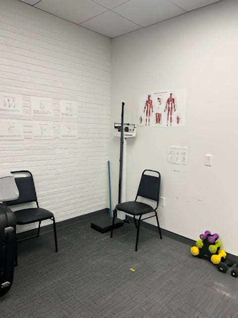 View of the exercise testing lab corner featuring seating, a standing scale, and anatomical charts on the wall
